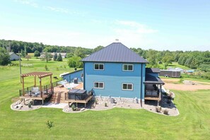 A two-story house with a deck, outdoor seating, and a well-maintained lawn.