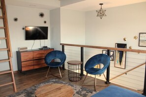 A modern living room with a TV, wooden furniture, and blue chairs. - 1900 FARMHOUSE (Wausau)
