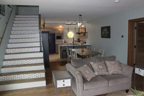 A staircase with patterned steps leading to a dining area with a round table and chairs.