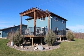 A two-story house with a wooden deck and outdoor seating area. - 1900 FARMHOUSE (Wausau)