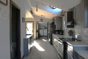 Una cucina con pavimento a spina di pesce, mobili bianchi e isola centrale.
