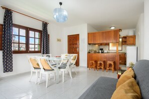 A dining area with a table and chairs, a kitchen with wooden cabinets, and a bar area.