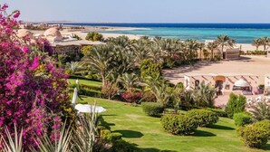 A coastal resort with palm trees, a beach, and a garden with vibrant flowers. - Floriana Dream Lagoon (Marsa Alam)