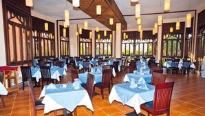 A spacious dining area with multiple tables set for guests, large windows allowing natural light, and a high ceiling with hanging lights. - Floriana Dream Lagoon (Marsa Alam)