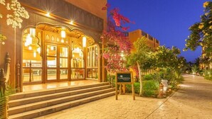 A warmly lit hotel entrance with traditional architecture, a signboard, and a well-maintained garden area. - Floriana Dream Lagoon (Marsa Alam)