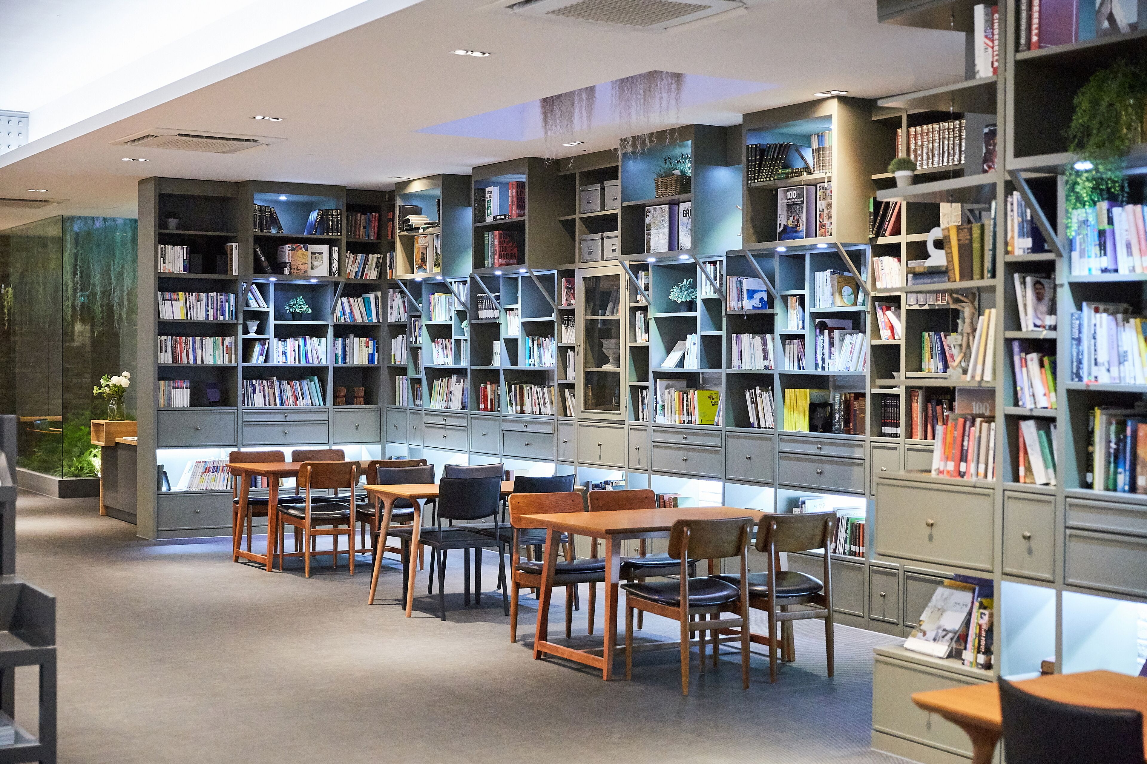 Une bibliothèque dotée de nombreuses étagères, de tables en bois et de chaises disposées pour la lecture.