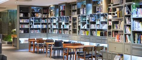 Une bibliothèque dotée de nombreuses étagères, de tables en bois et de chaises disposées pour la lecture.
