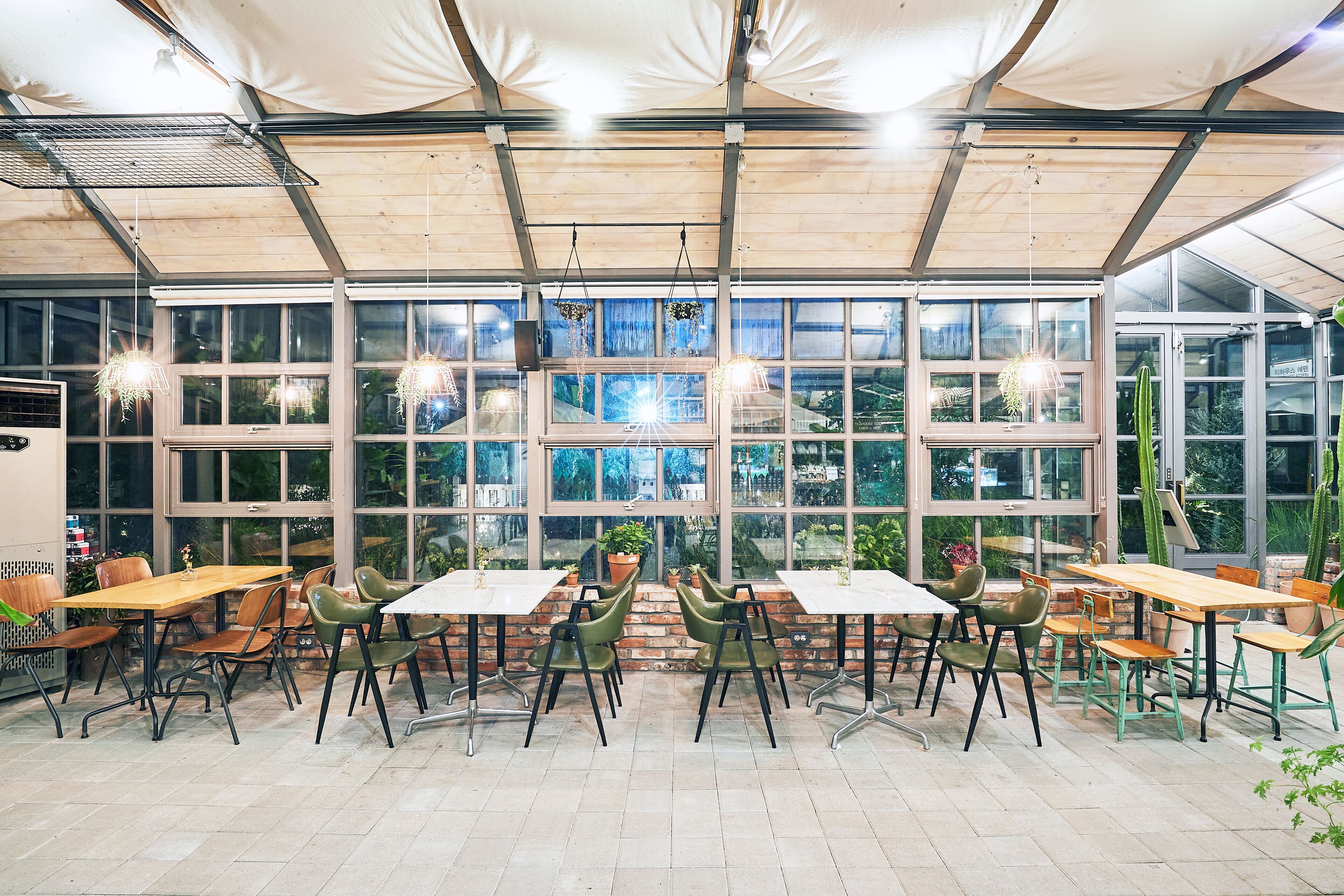 Un vaste espace de restauration intérieur, doté de nombreuses tables et chaises, de grandes fenêtres et de luminaires suspendus.