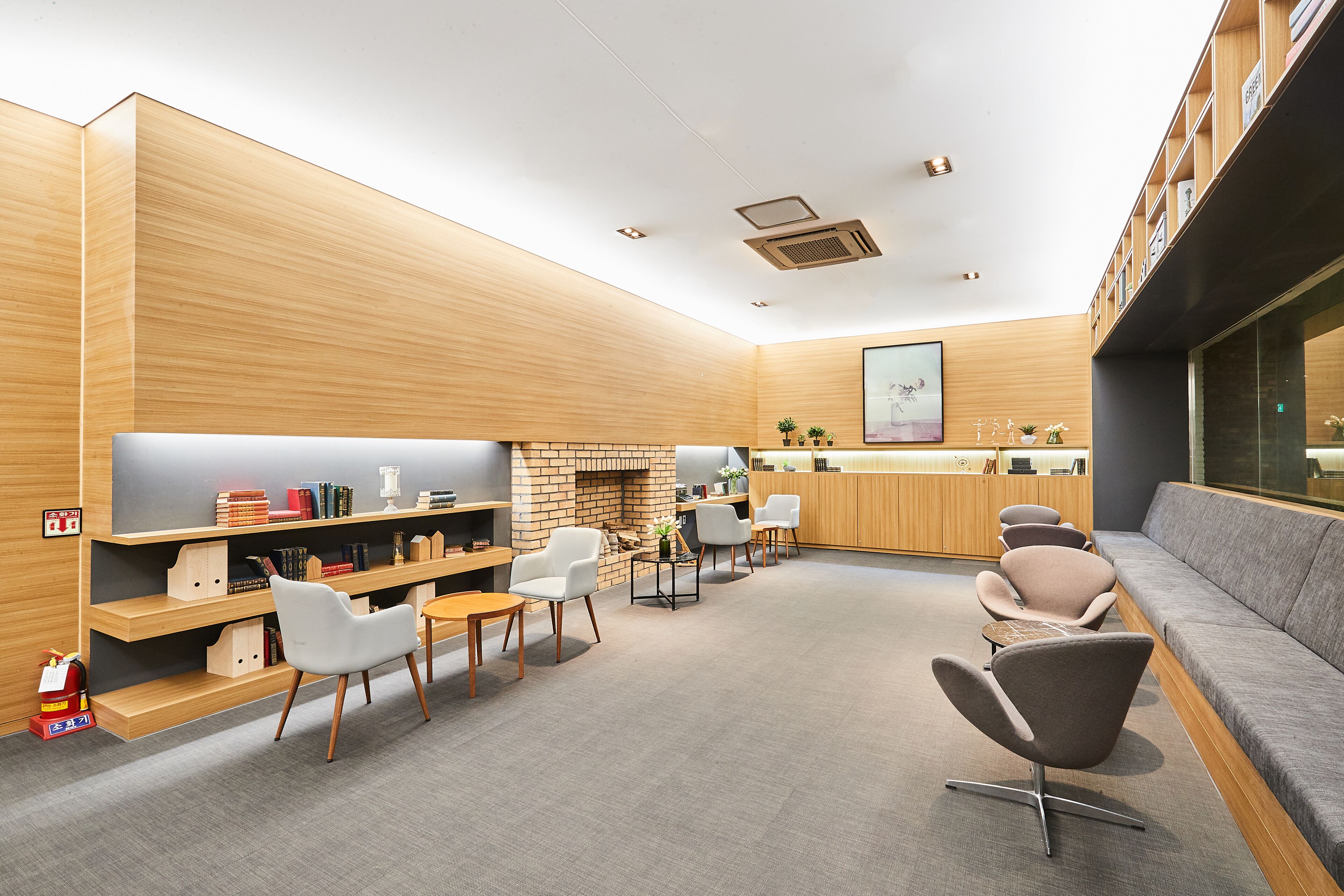 A modern lounge area with a fireplace, comfortable seating, and a bookshelf.