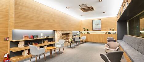 A modern lounge area with a fireplace, comfortable seating, and a bookshelf.