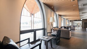 A spacious lobby with large windows, modern furniture, and a high ceiling with wooden slats. - Eden Paradise Hotel (Icheon)