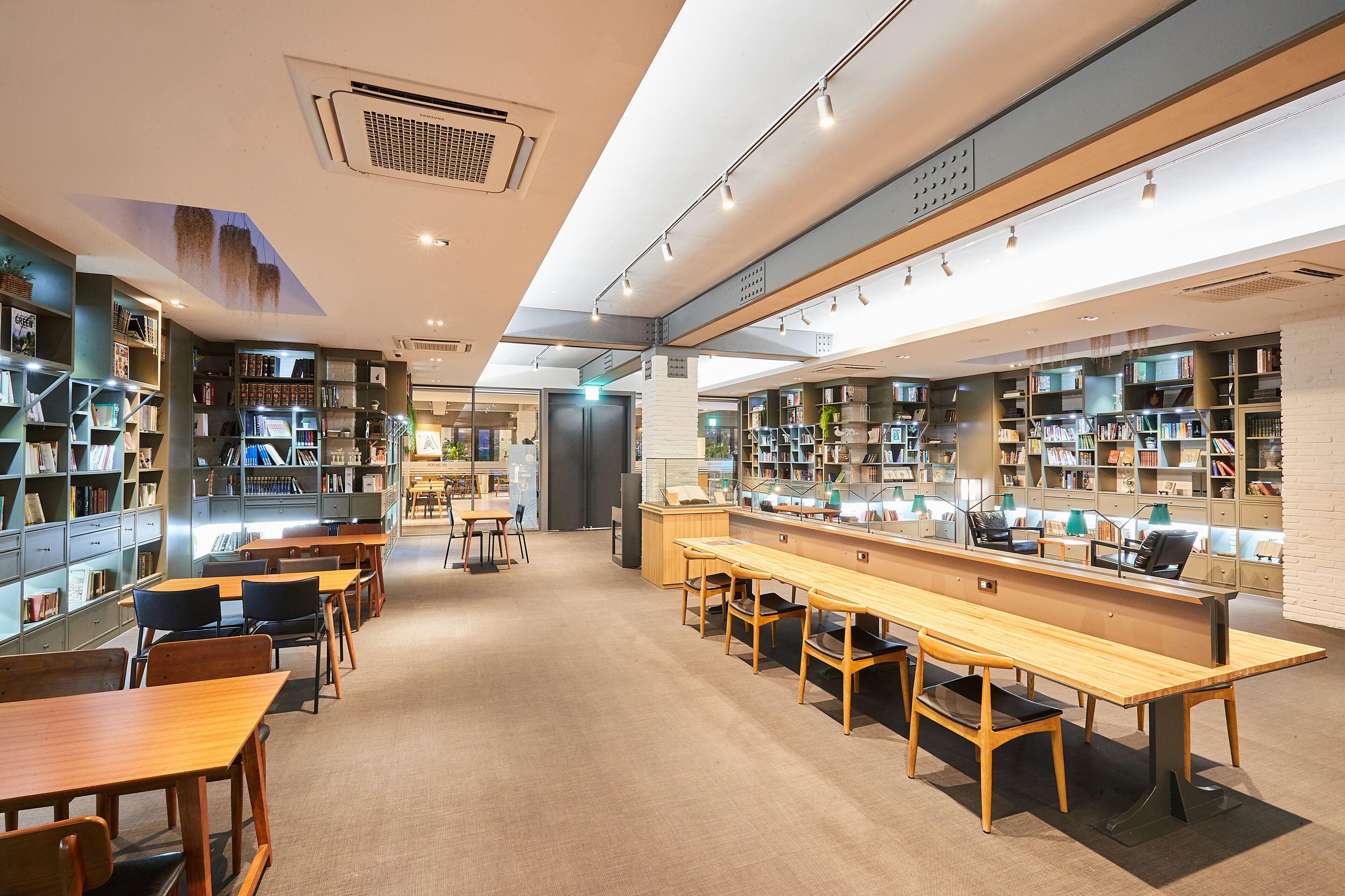 A modern library with bookshelves, tables, and chairs.