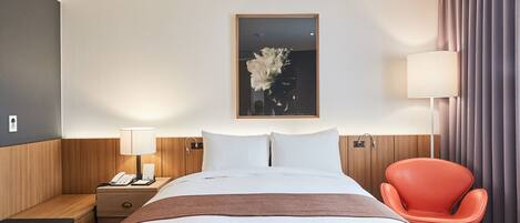 Una habitación de hotel con cama, mesita de noche, lámpara y una silla naranja.