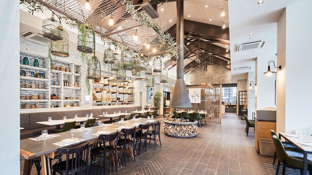 A modern restaurant with a long counter, multiple seating areas, and hanging plants. - Eden Paradise Hotel (Icheon)