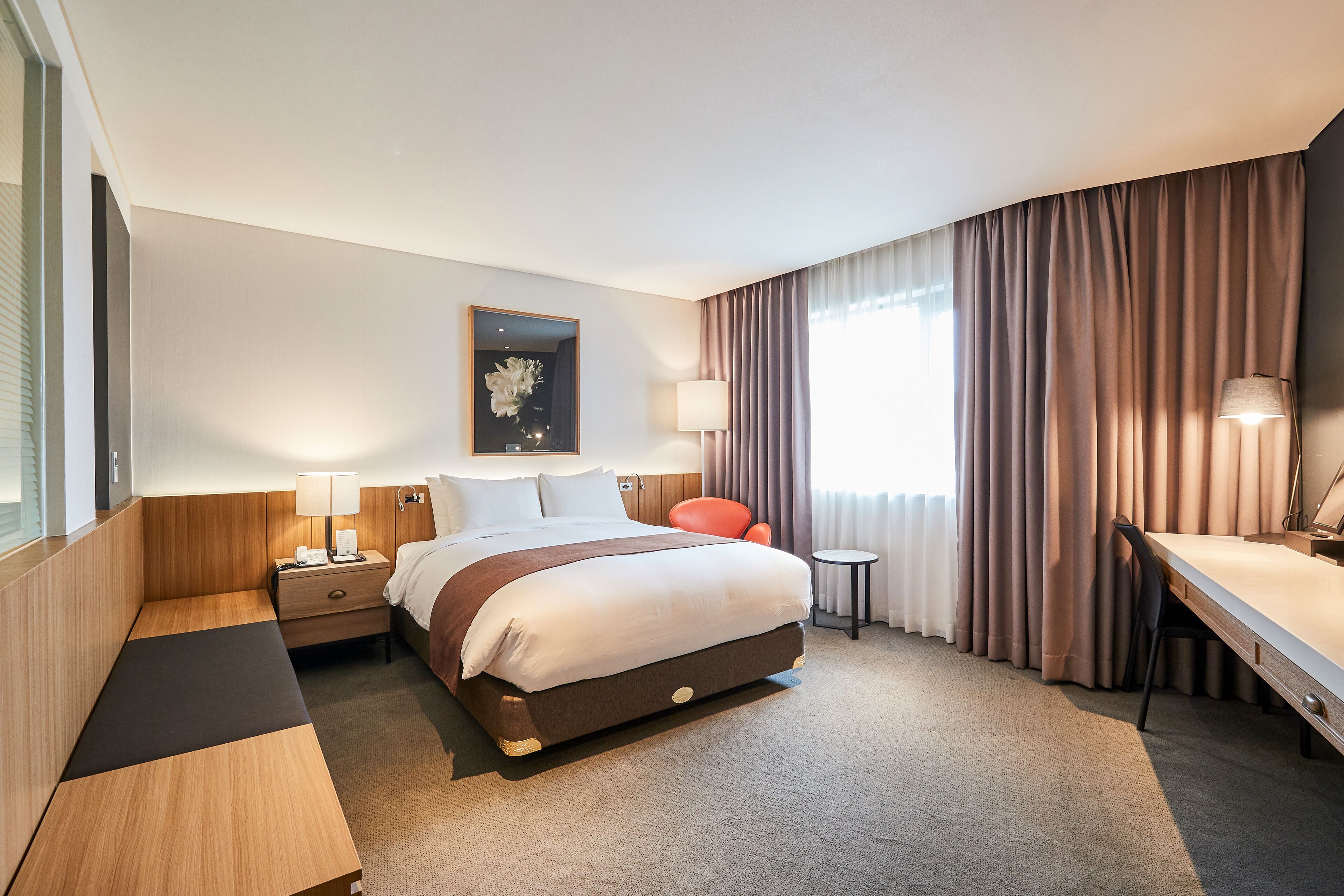 A hotel room with a bed, bedside tables, a desk, and a chair.