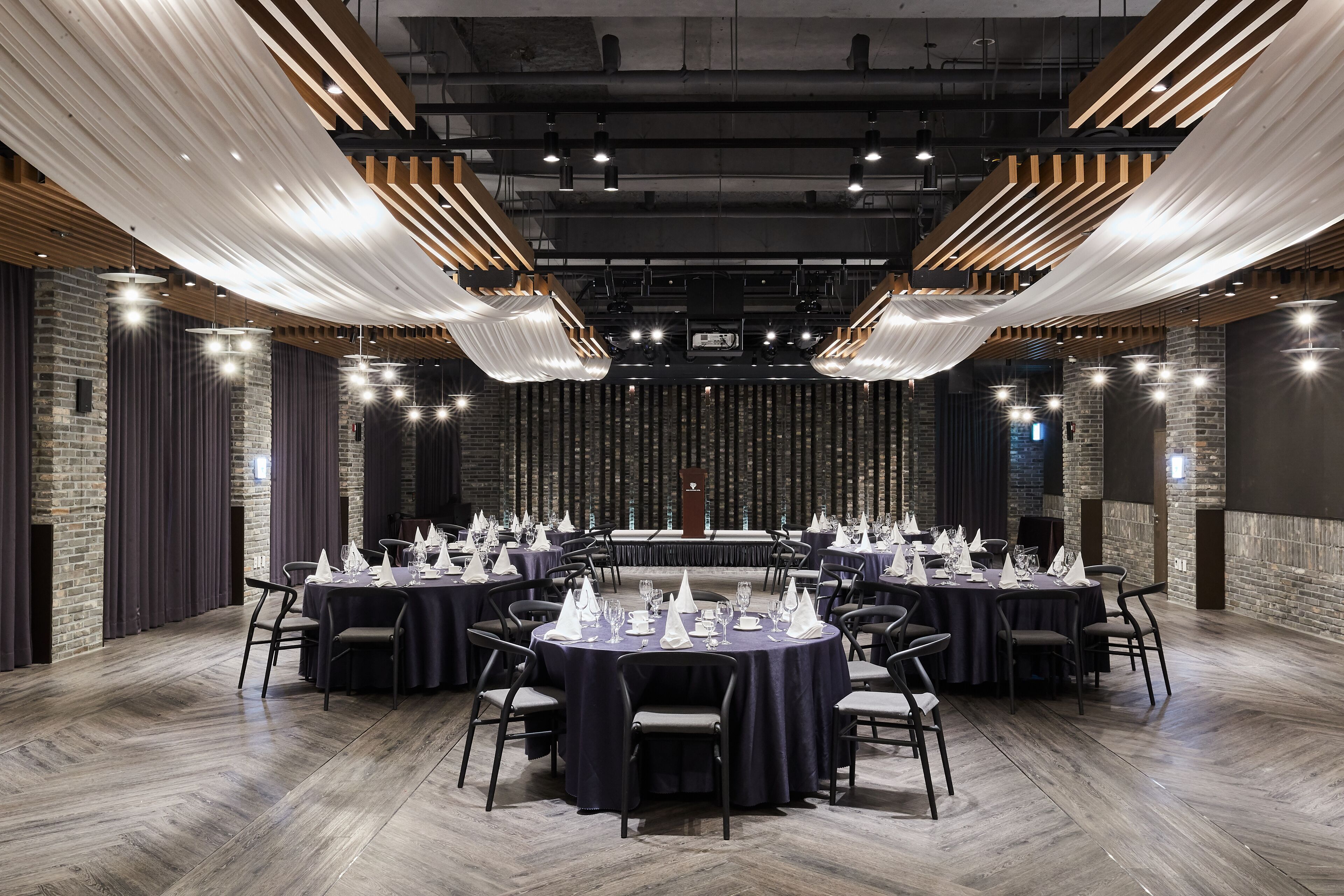 Un salón de conferencias con mesas redondas, sillas y un escenario con un atril.
