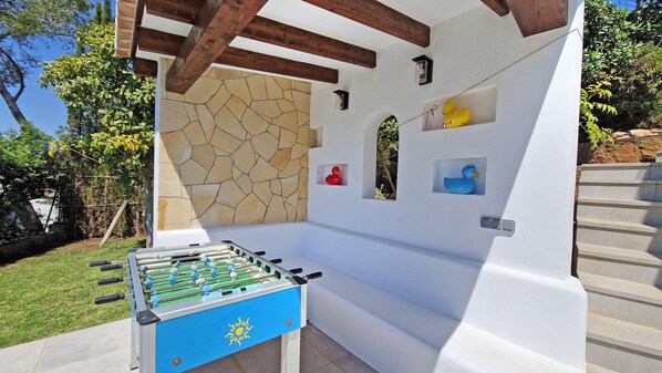 A foosball table under a wooden pergola with stone walls and decorative elements. - Casa Sabene - Javea, Costa Blanca (Javea)