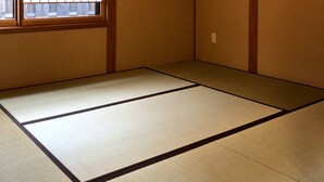 A traditional tatami mat room with a shoji screen window, wooden beams, and a ceiling light. - Mokuren (Kyoto)