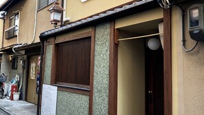 A traditional building with a tiled entrance, a wooden door, and a small porch area. - Mokuren (Kyoto)