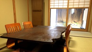 A traditional Japanese-style room with tatami mat flooring, a wooden table, and four wooden chairs. - Mokuren (Kyoto)