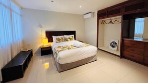 A neatly arranged bedroom with a bed, bedside table, lamp, and a wardrobe. - Kidsfirst Apartment 3 (Suva)