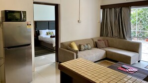 Ein modernes Hotelzimmer mit Bett, Sofa, Esstisch, Kühlschrank und Mikrowelle.