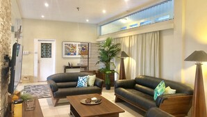 A spacious living area with two black leather sofas, a wooden coffee table, and a large potted plant. - The Williamson House (Suva)