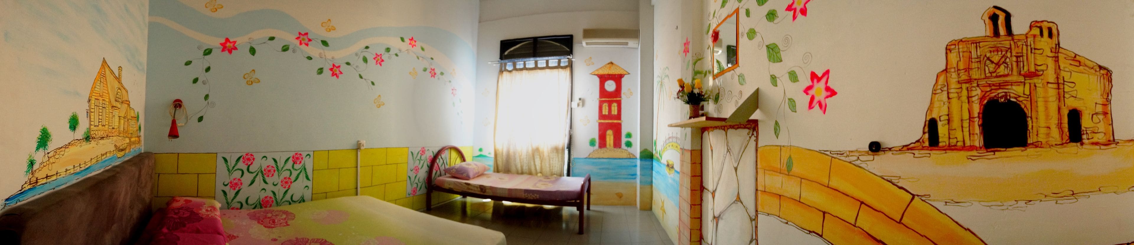 A room with a bed, a chair, and a wall with colorful murals.