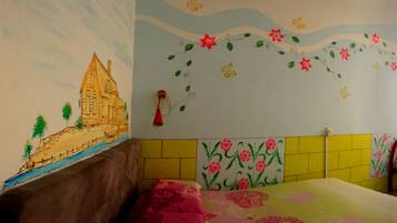A room with a bed, a chair, and a wall with colorful murals.