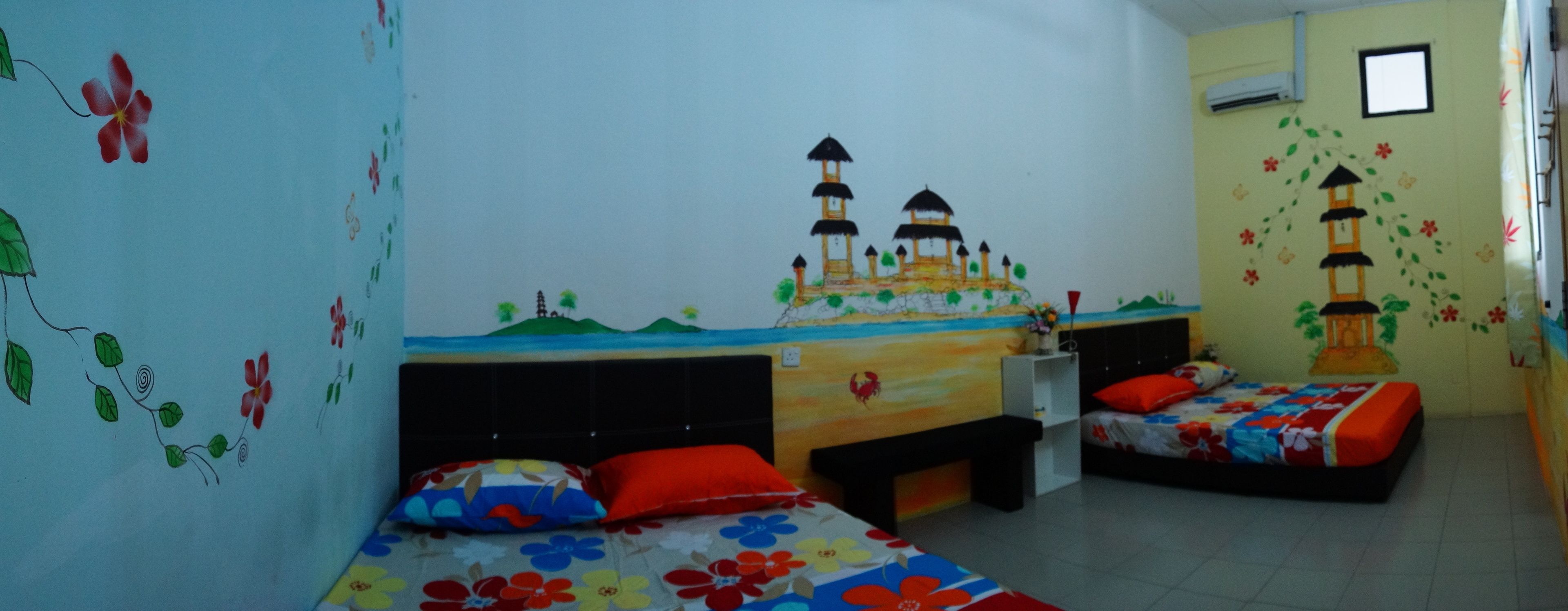 A room with two beds, a small desk, and a wall mural.