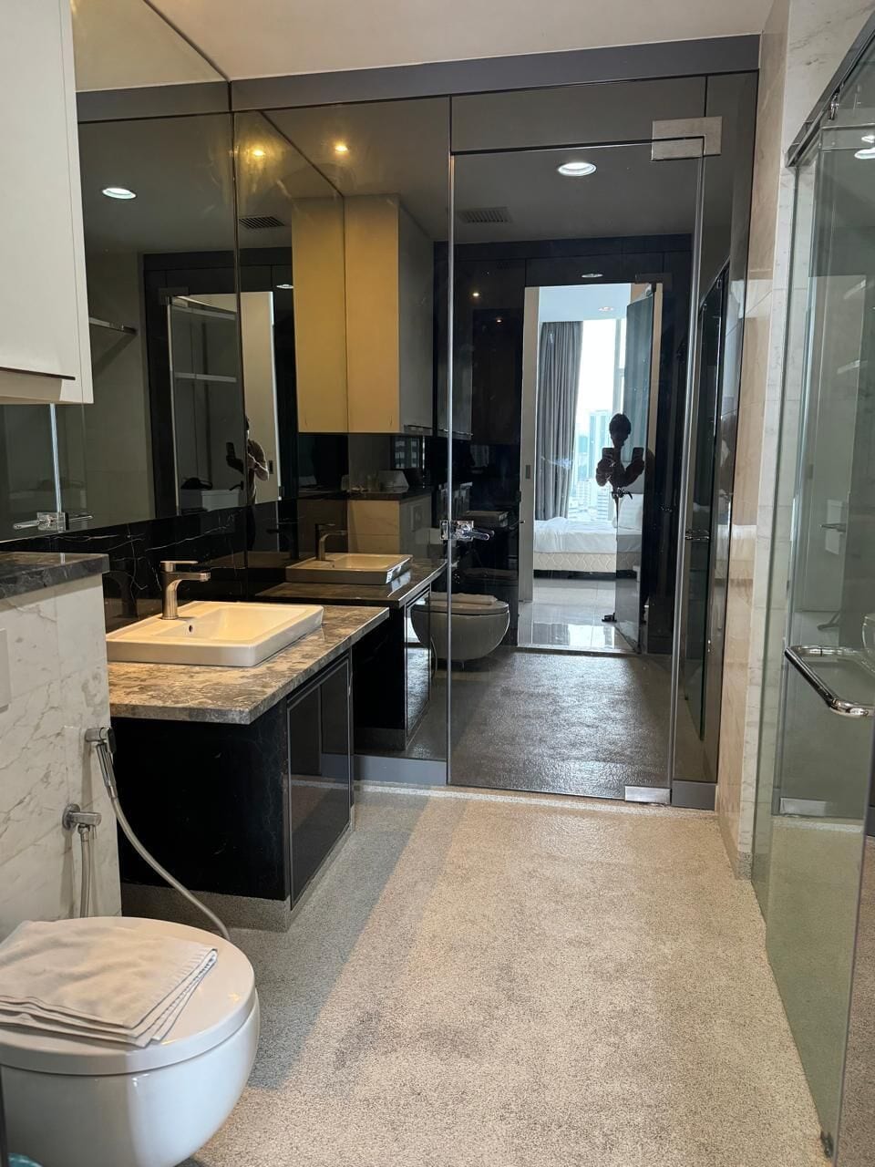 Un baño moderno con cabina de ducha de vidrio, inodoro blanco y encimera de mármol.