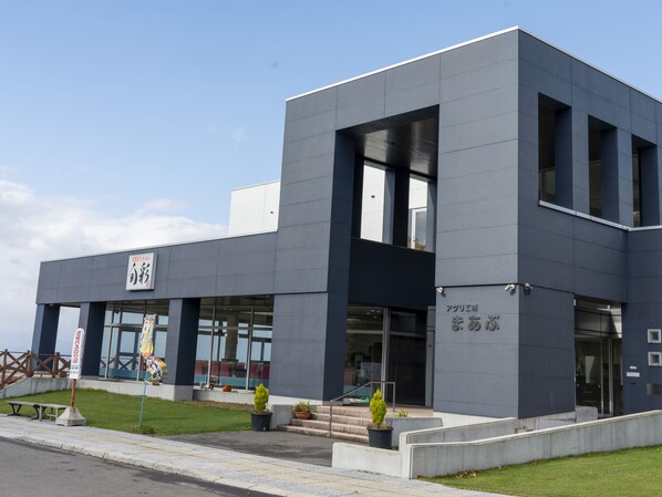 Un edificio moderno con techo plano, ventanas grandes y un letrero con caracteres japoneses.