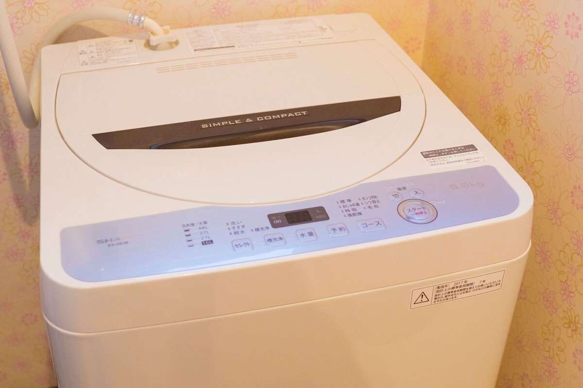 A compact, white washing machine with a control panel featuring multiple buttons and a digital display.