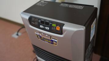 A compact, silver and black refrigerator with a digital control panel, a power cord, and a sticker.