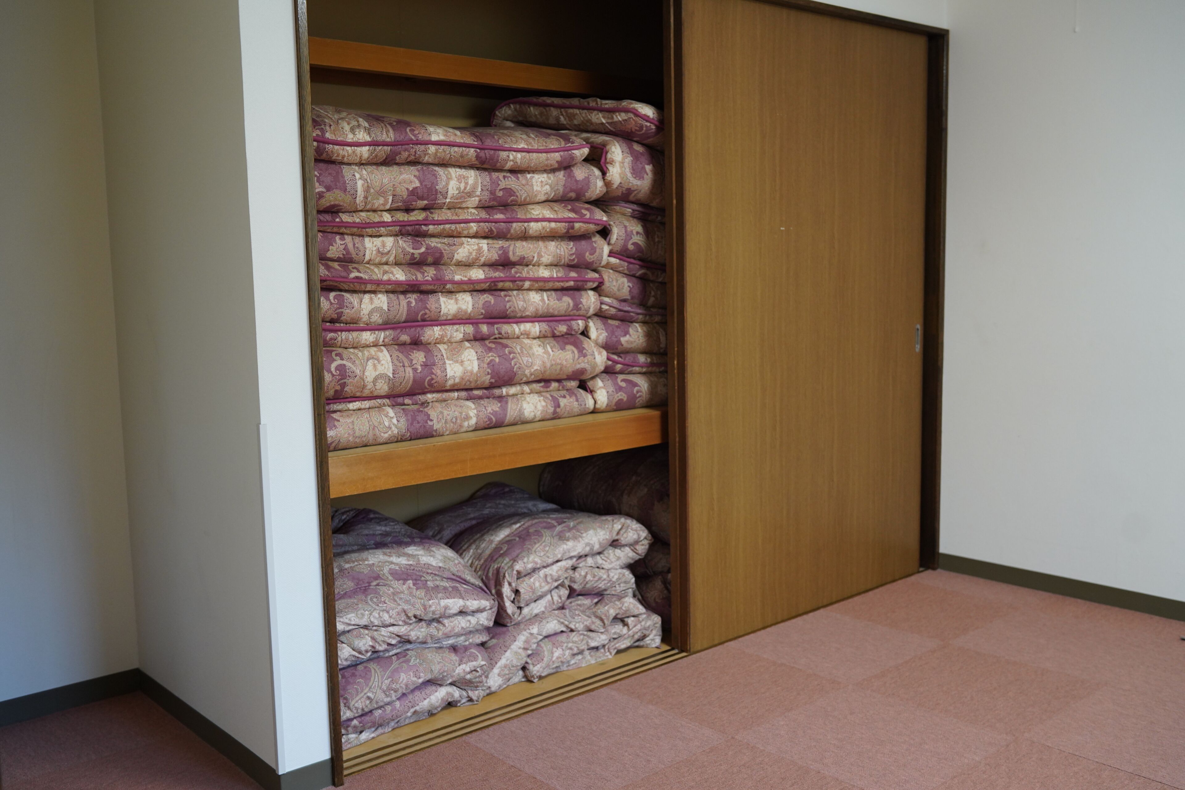 A closet with multiple shelves, each holding folded blankets or linens.