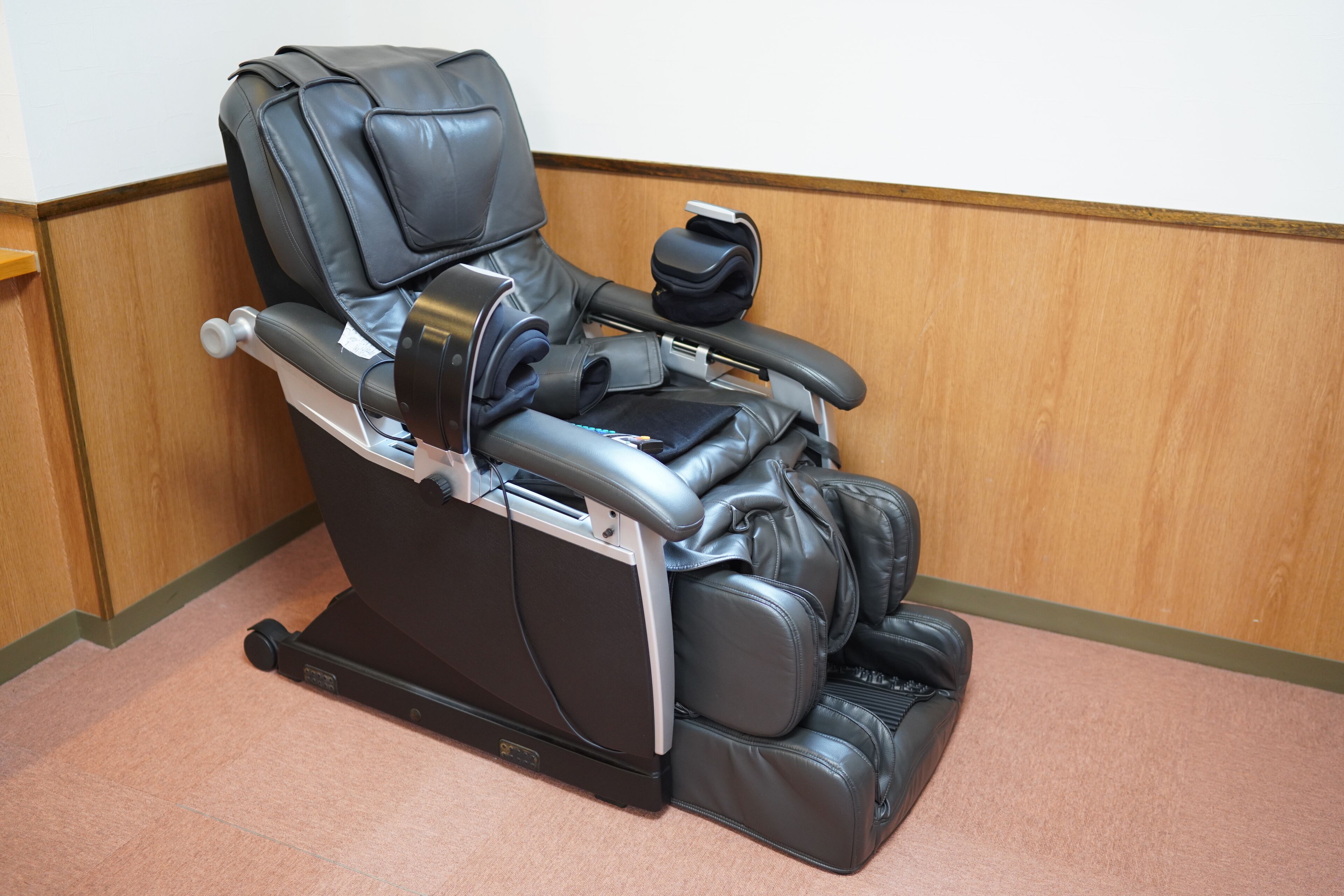 Un fauteuil de massage doté d’un repose-pieds, d’un appui-tête réglable et d’un panneau de commande.