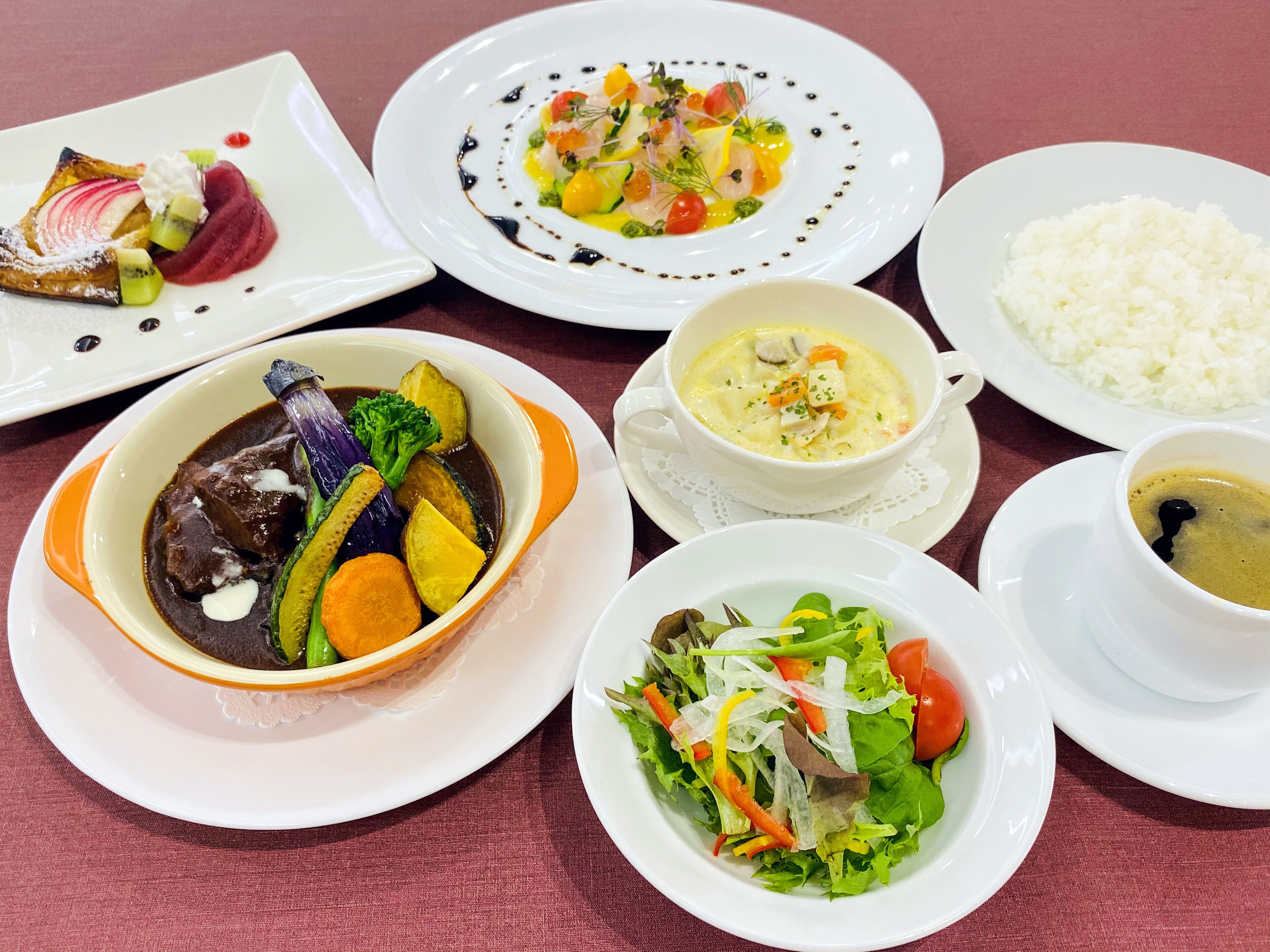 Un assortiment de plats comprenant une soupe, une portion de riz, une salade et un dessert.