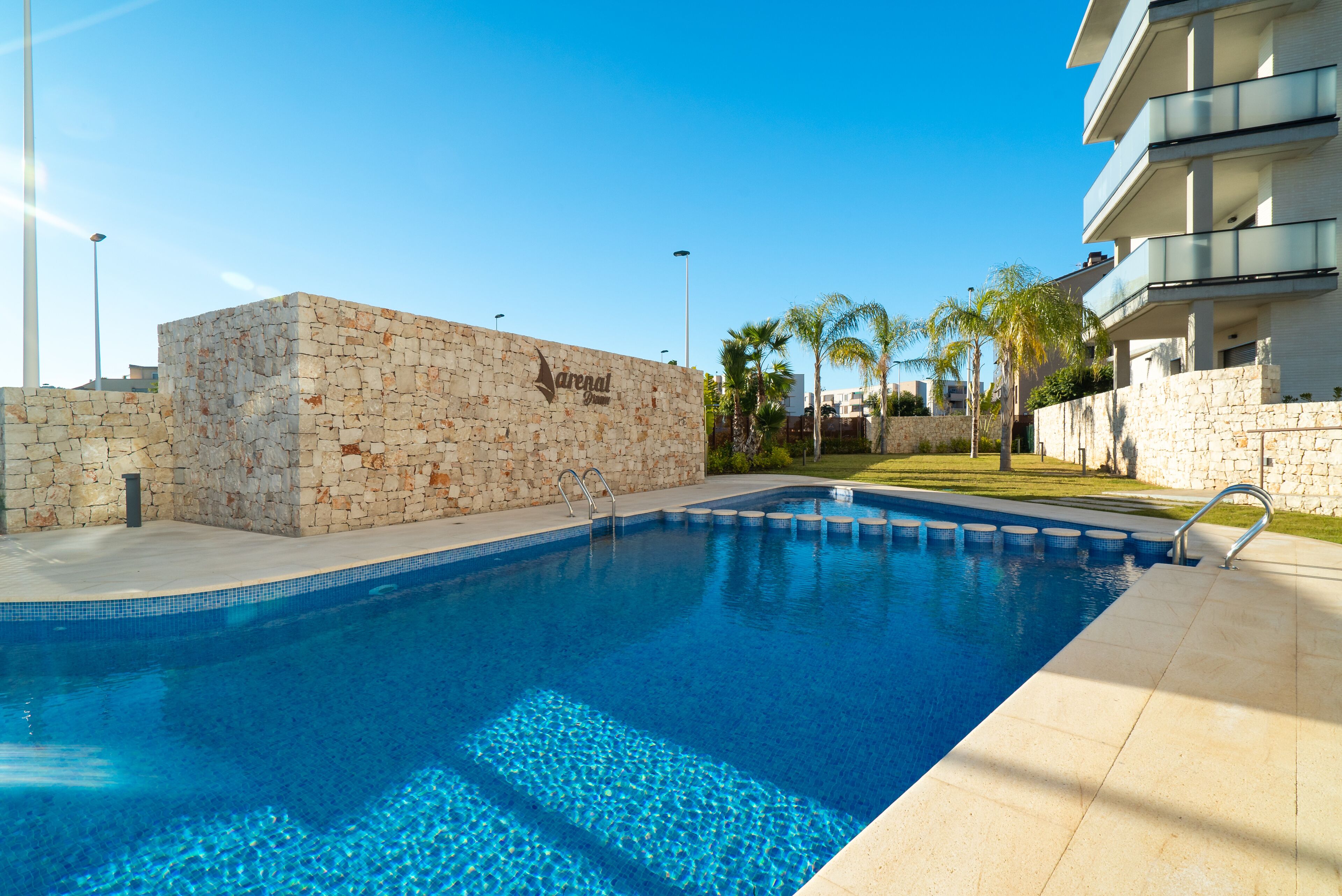 A swimming pool with stone walls and a clear blue water surface.