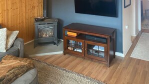 Ein Wohnzimmer mit Holzwänden, einem Kamin, einem Fernseher und einem Sofa.