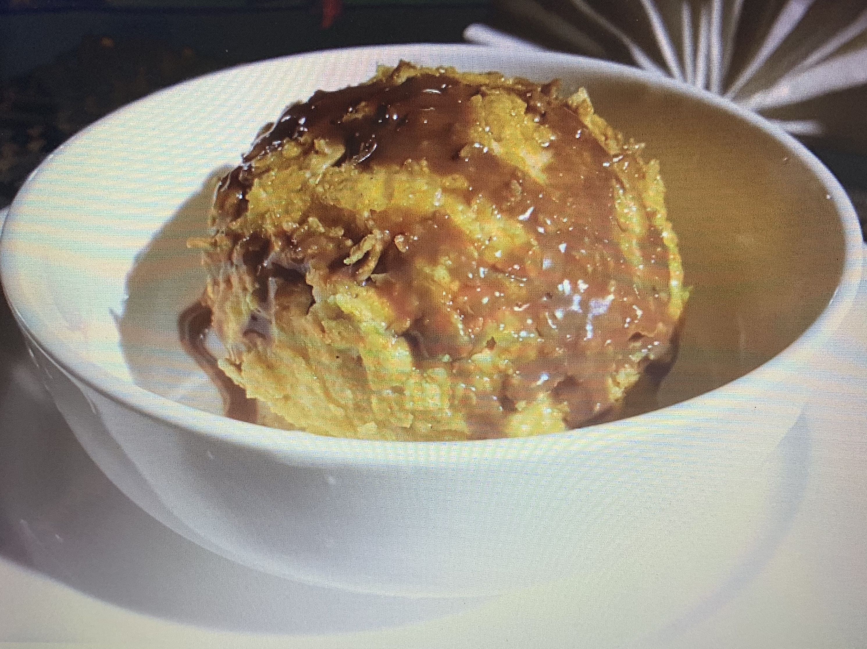 A bowl of food with a glossy topping, possibly a dessert or a savory dish, served in a white bowl.