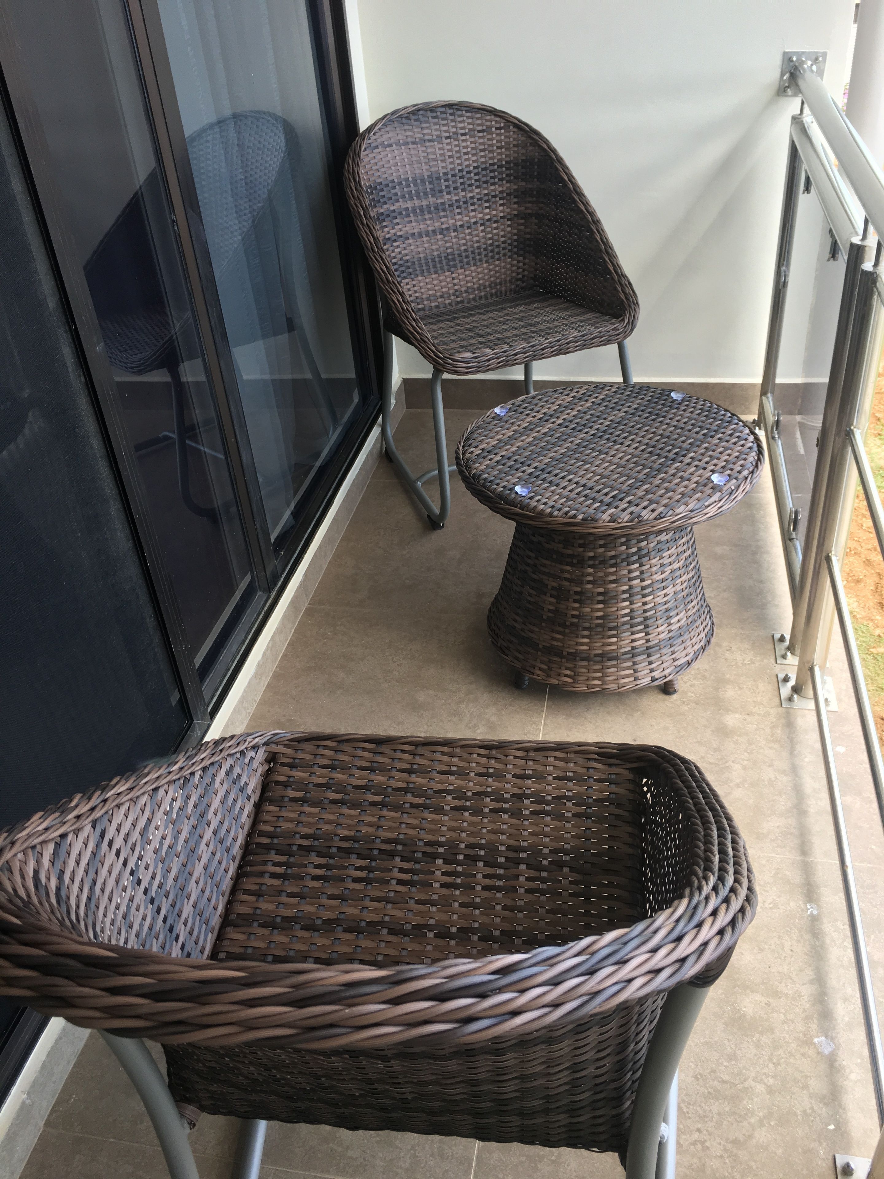 A balcony with wicker furniture, including a chair and a small table.