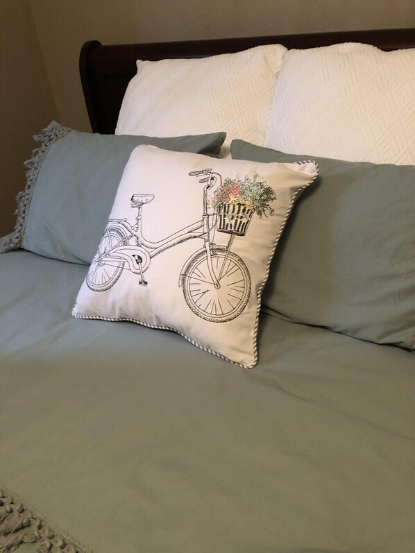 A bed with a grey mattress and a pillow featuring a bicycle design.