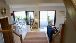 A spacious living area with a dining table and chairs, a sofa, and a staircase leading to an upper floor.