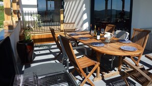 An outdoor dining area with a wooden table set for four, surrounded by chairs.