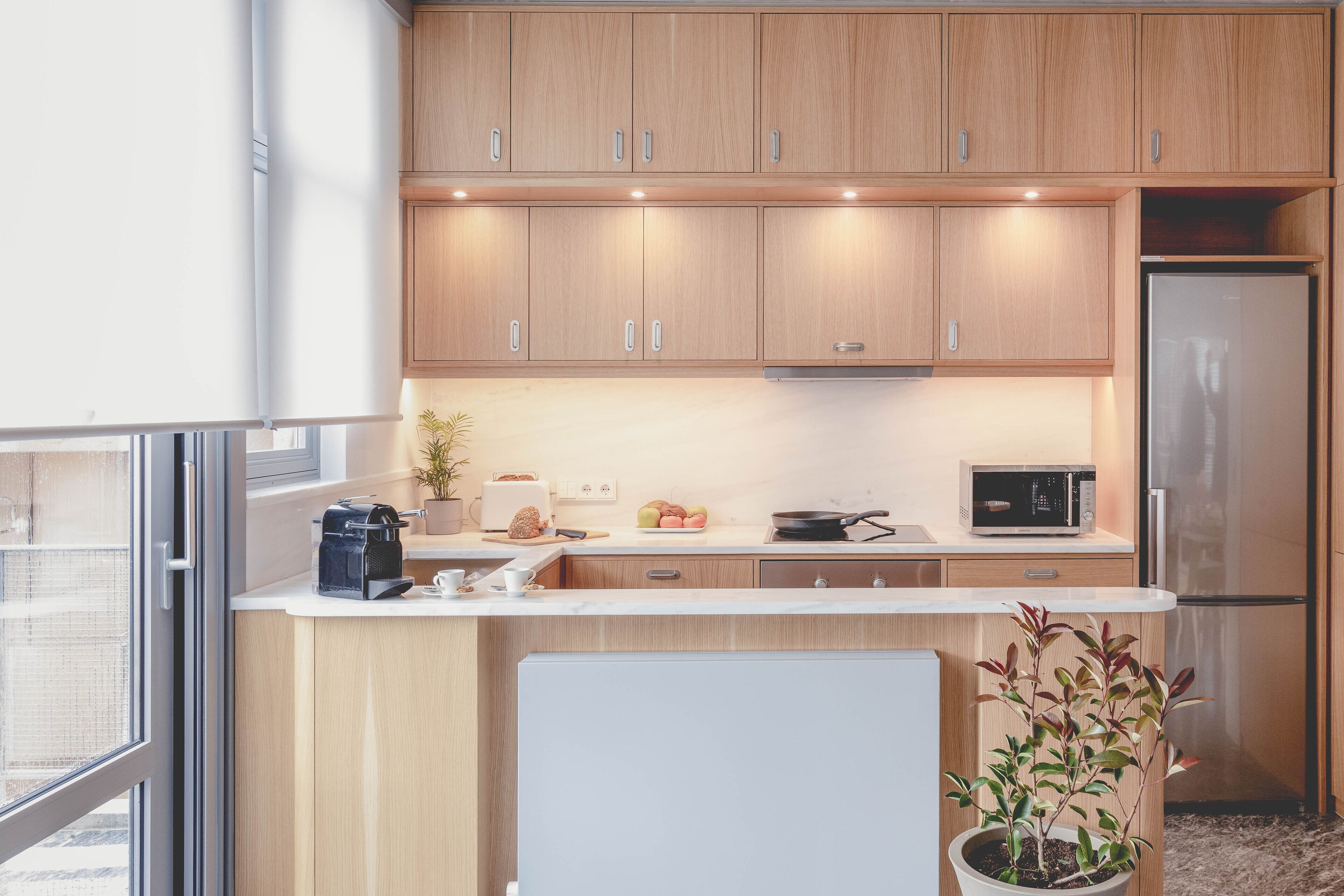 A modern kitchen with wooden cabinets, a refrigerator, a microwave, and a coffee maker.