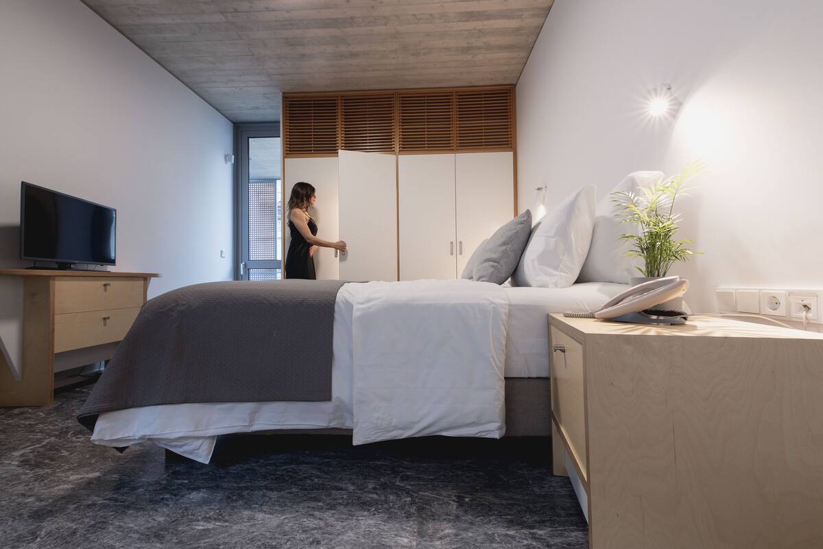 A modern bedroom with a bed, bedside table, and a TV on a wooden dresser.