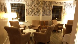 A room with a round table, six armchairs, and floral wallpaper. - Björnforsens Turist & Konferens Hotell (Bjorna)