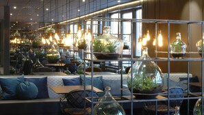 A modern interior with seating areas, glass containers with plants, and hanging light fixtures. - Björnforsens Turist & Konferens Hotell (Bjorna)