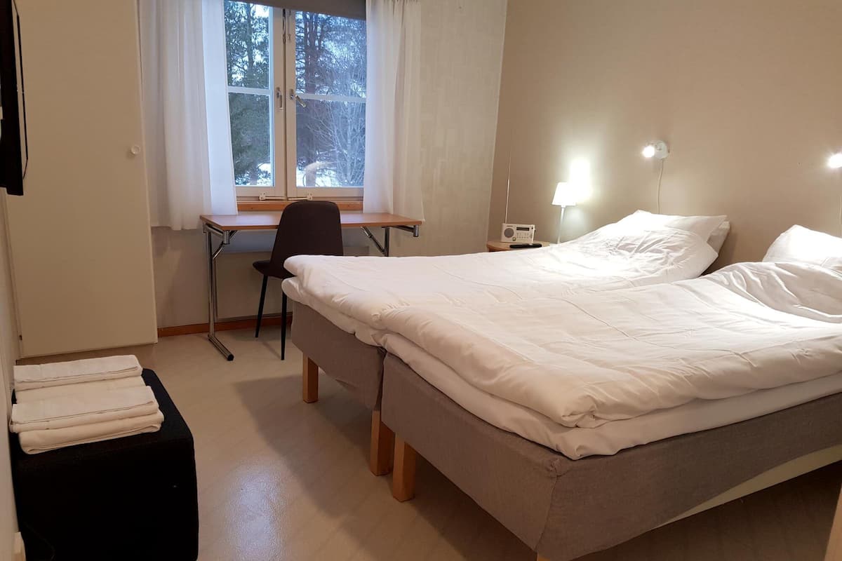 Une chambre à coucher comprenant un lit, un bureau, une chaise et une table de chevet avec une lampe.
