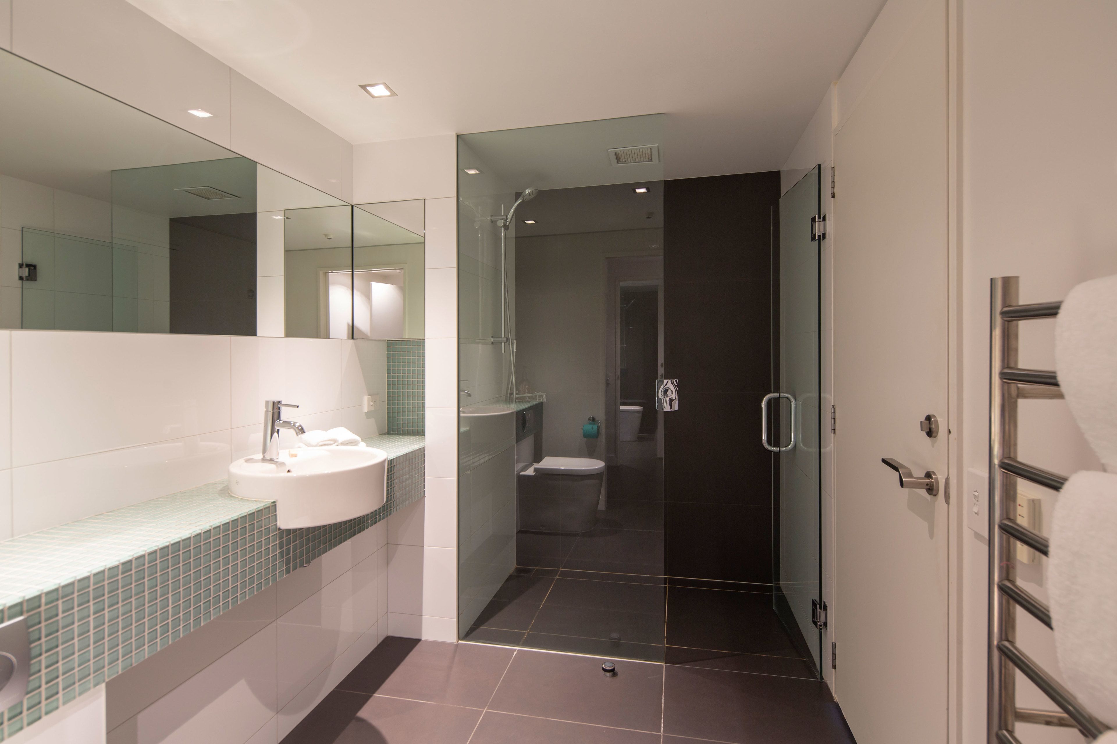 A modern bathroom with a glass-enclosed shower, a white sink, and a mirror.